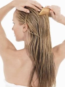uma mulher penteando seus cabelos lavados