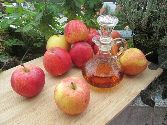 Maçã fresca e uma garrafa de vinagre de cidra de maçã em cima da mesa