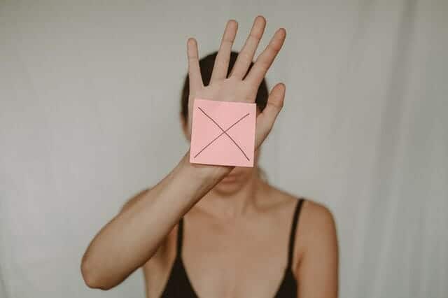  uma mulher triste segura uma caixa de papelão com um x à sua frente