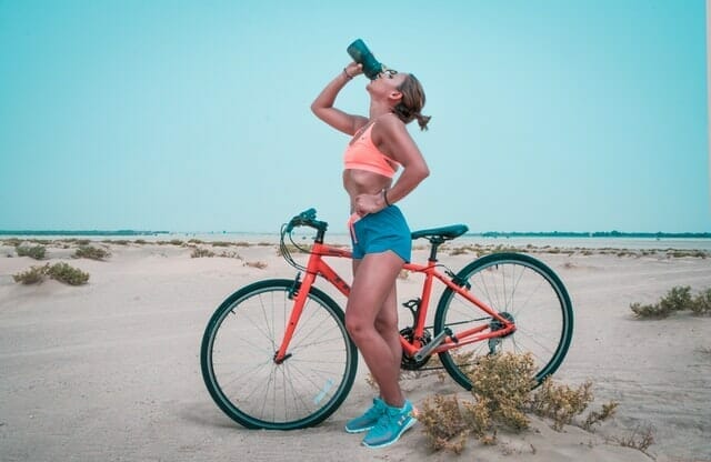  mulher bebe água de uma garrafa depois de um passeio de bicicleta