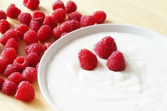  iogurte numa tigela, junto a uma framboesa
