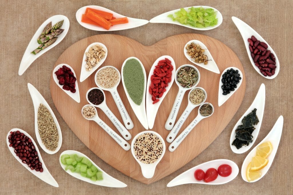  Ervas e outros produtos saudáveis encontram-se sobre uma tábua de cortar em forma de coração