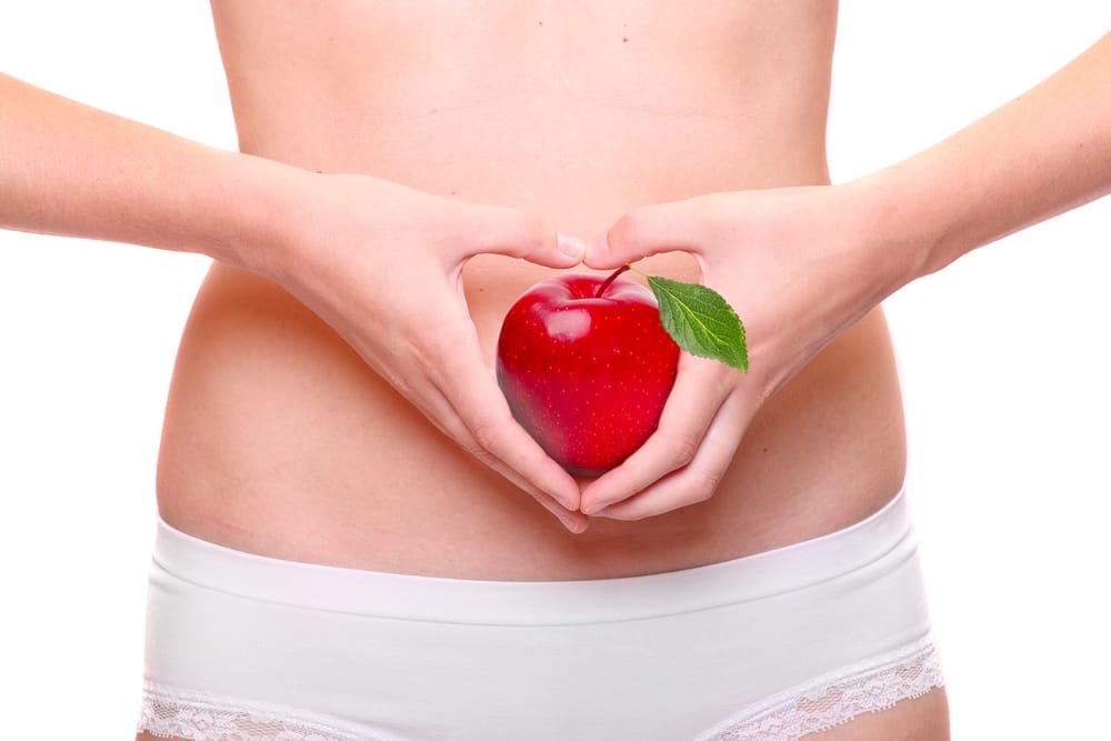  uma mulher segura uma maçã junto ao estômago